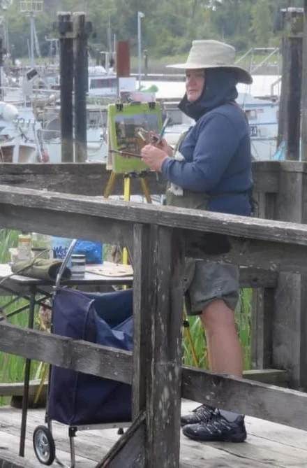 Artist painting outside at a dock
